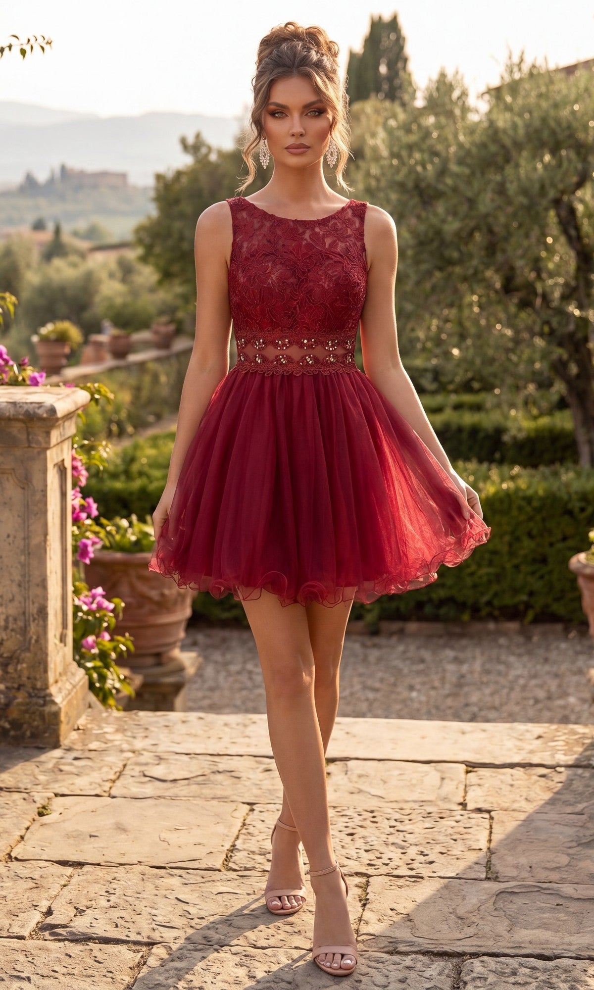 Wearing the Chicas C1107 short homecoming dress in burgundy, this woman stands on a stone path in a garden, showcasing the sleeveless fit-and-flare style with a lace bodice and floral-detailed tulle skirt.